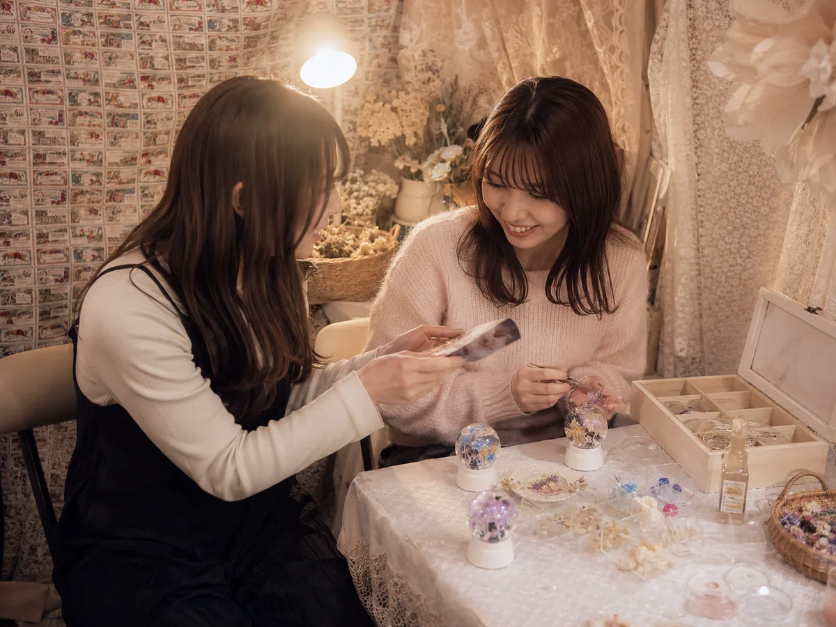池袋で久しぶりに会った友達同士が写真を見ながらスノードームを作る様子
